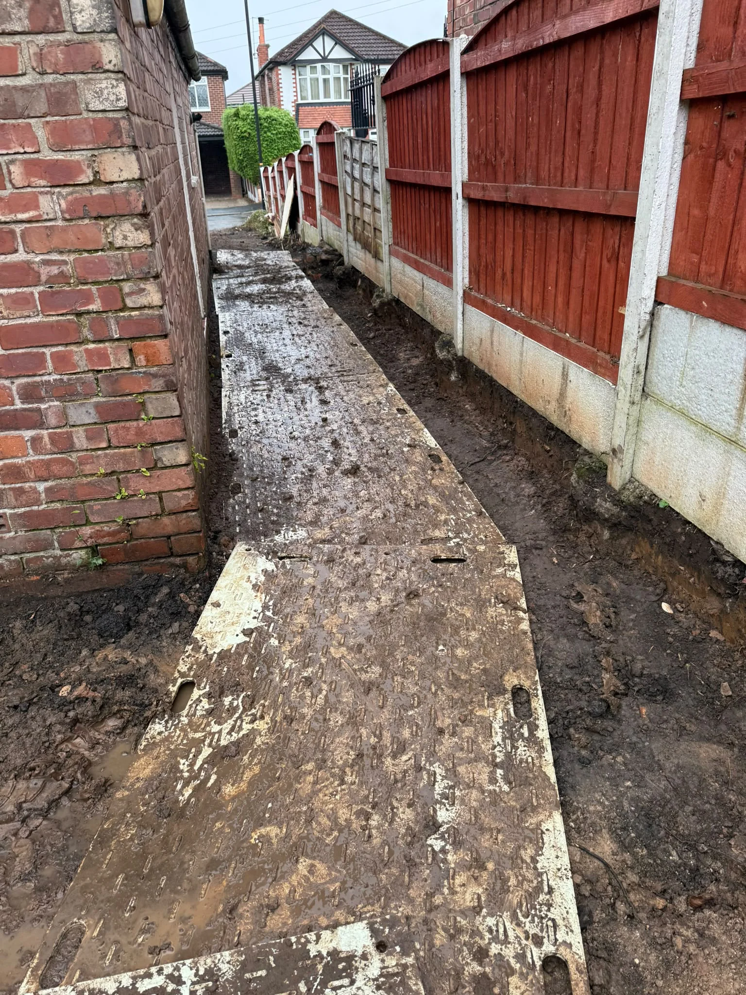 Ground protection boards along the narrow side access beside the house