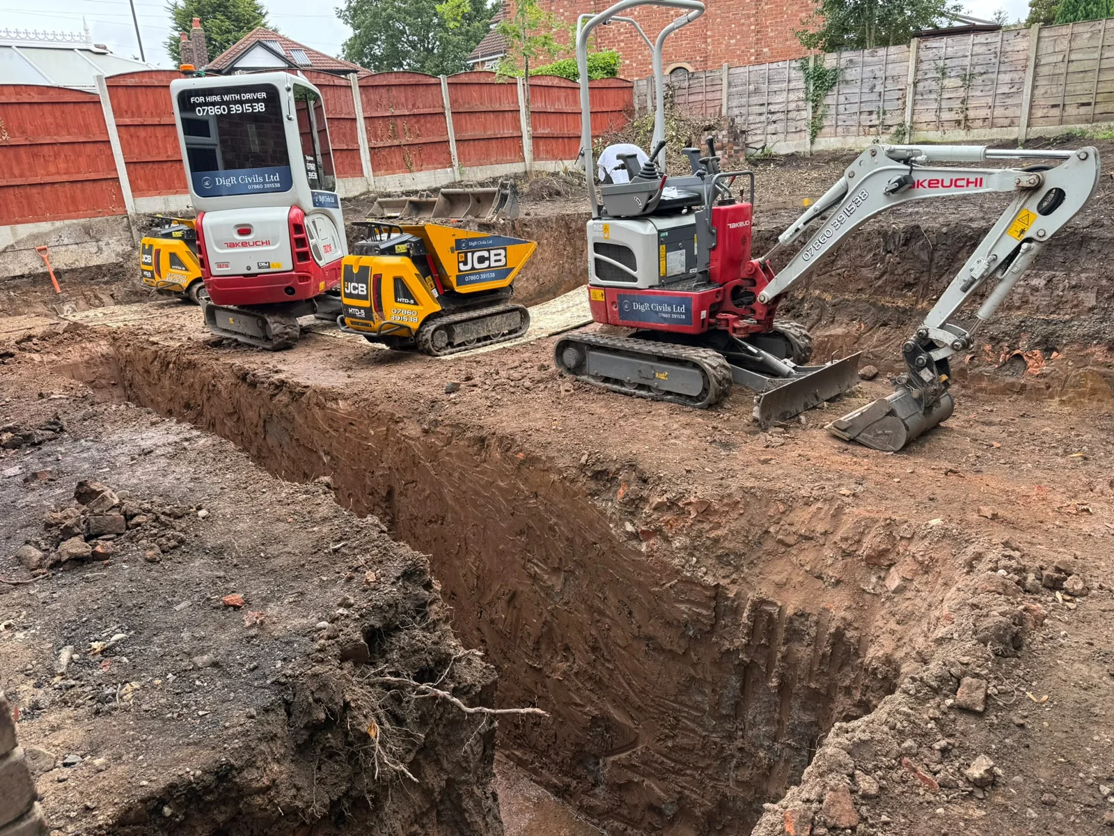Mini and micro excavators with tracked dumpers beside the foundation trenches