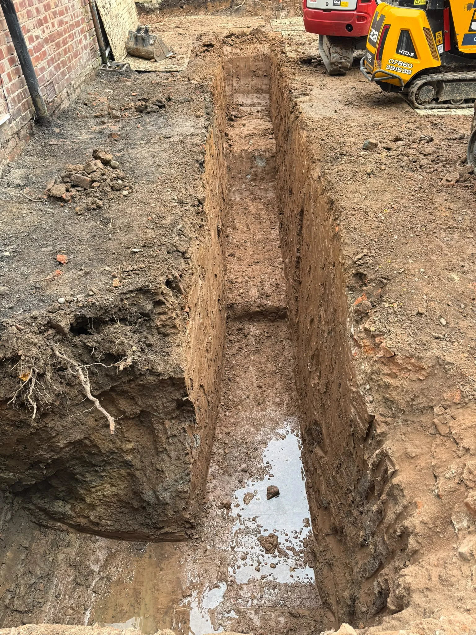Foundation trench excavated beside the existing brick house
