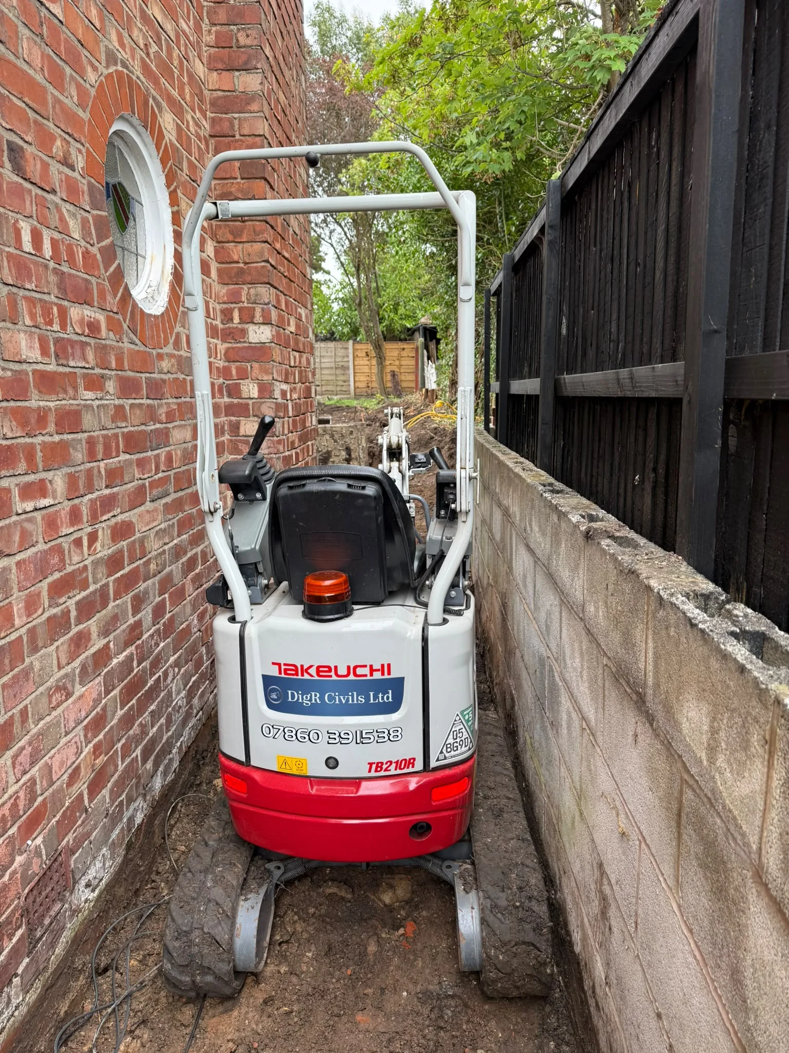 Micro digger moving through a narrow residential passage
